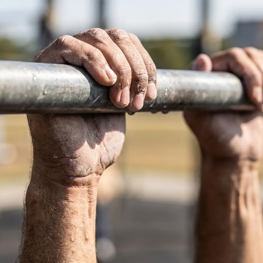 Chalked hands gripping a steel pull-up bar